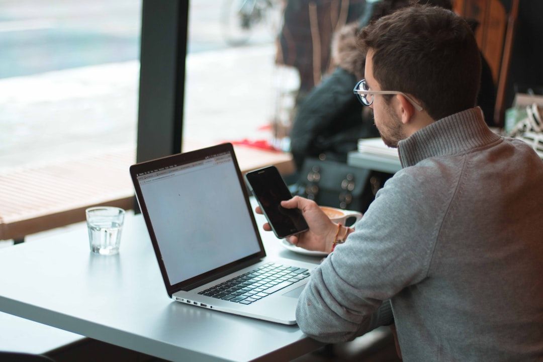 Person arbeitet gleichzeitig mit Laptop und Smartphone.