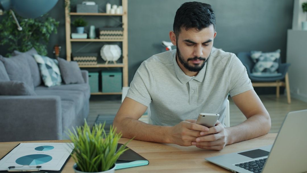 Person vergleicht Zahlen am Laptop und auf dem Smartphone.