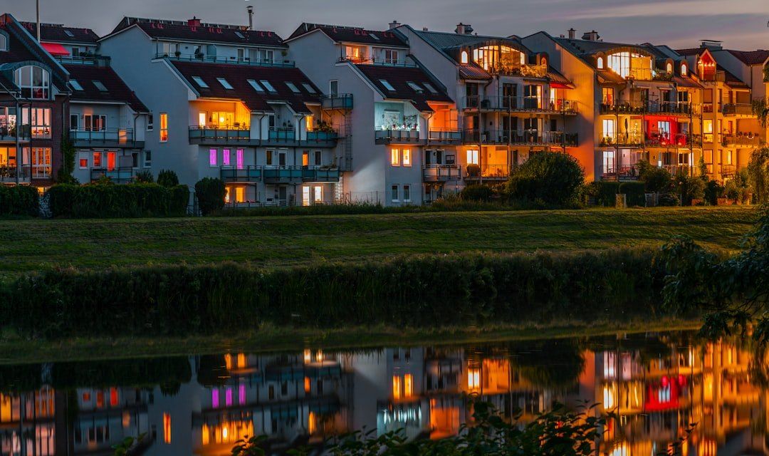 Beleuchtete Apartmenthäuser an einem Fluss in der Dämmerung.